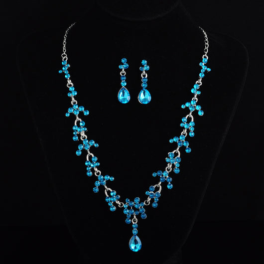 Silver-tone bridal jewelry set with a rhinestone floral necklace and matching teardrop dangle earrings on a black display. - Image 3