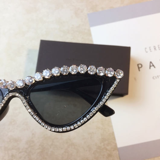Two pairs of cat-eye sunglasses, one black with clear rhinestones and one pink with pink rhinestones, on a light surface. - Image 2