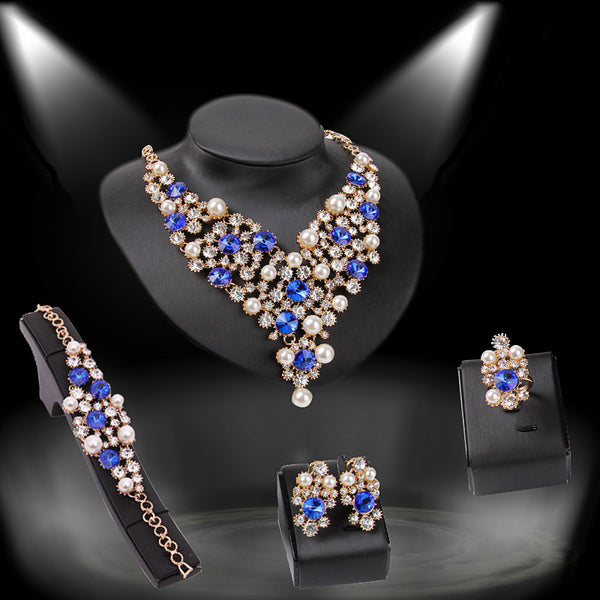 Four-piece bridal jewelry set with gold-toned necklace, earrings, bracelet, and ring, featuring amber and clear rhinestones with faux pearls.