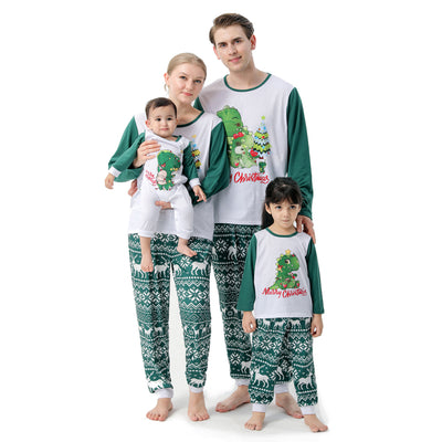 Woman in a Christmas pajama set with a white top, green sleeves, dinosaur graphic, and green fair isle pants. - Image 2
