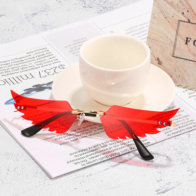 Purple wing-shaped rimless sunglasses with gold-colored metal arms and black ear tips on a white background. - Image 2