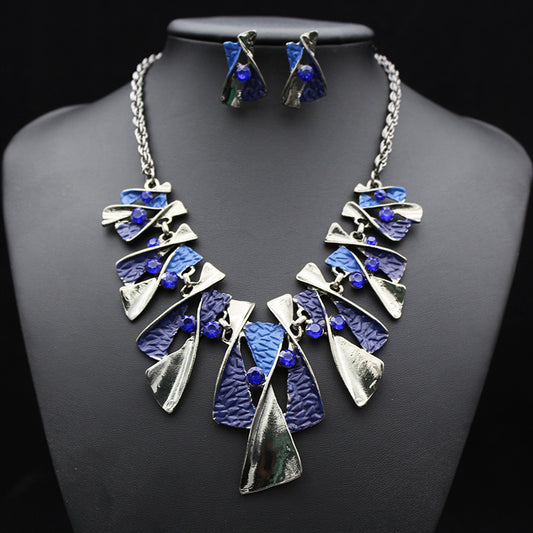 Silver and blue abstract fashion necklace and matching stud earrings set with blue rhinestones on a black mannequin. - Image 2