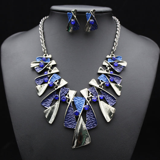 Silver and blue abstract fashion necklace and matching stud earrings set with blue rhinestones on a black mannequin. - Image 2