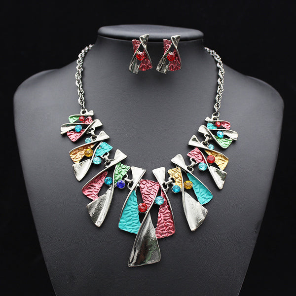 Silver and blue abstract fashion necklace and matching stud earrings set with blue rhinestones on a black mannequin.