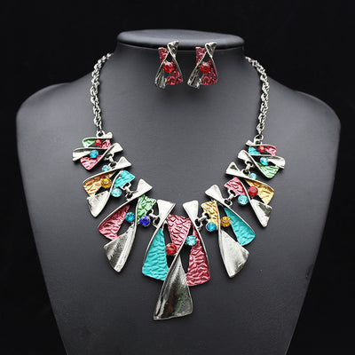 Silver and blue abstract fashion necklace and matching stud earrings set with blue rhinestones on a black mannequin.