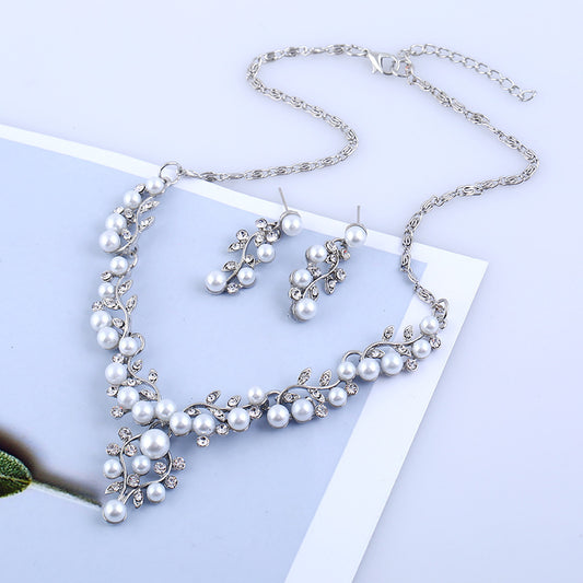 Gold-toned necklace and matching stud earrings set with vine-like design, adorned with white faux pearls and clear rhinestones.