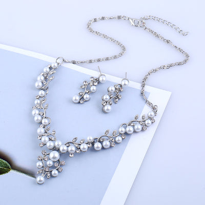 Gold-toned necklace and matching stud earrings set with vine-like design, adorned with white faux pearls and clear rhinestones.