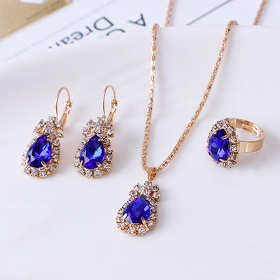 Red teardrop rhinestone necklace, matching dangle earrings, and adjustable ring set in gold-tone metal. - Image 3