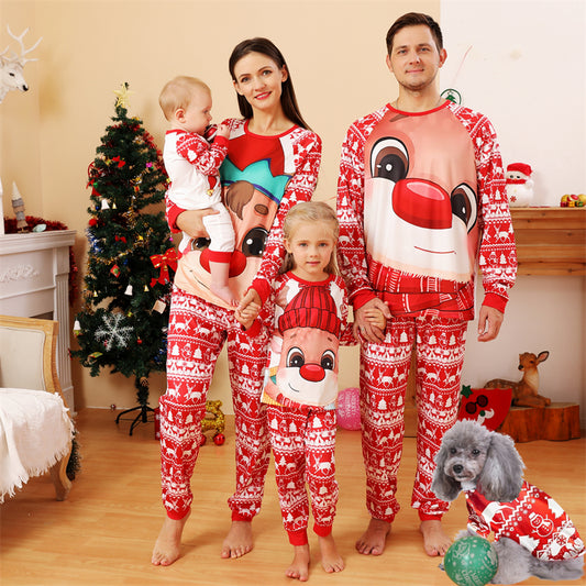 Baby wearing a red and white Christmas pajama set with a fawn graphic, sitting on a white blanket.