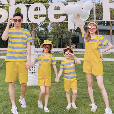 Family of four wearing matching yellow and blue striped t-shirts with daisy appliques. Mother and daughter wear yellow short overalls, father and son wear yello - Image 4
