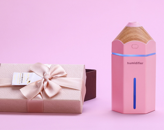 Light blue pencil-shaped mini humidifier with wood-grain top and glowing green light, next to a white teacup and pink gift box. - Image 4