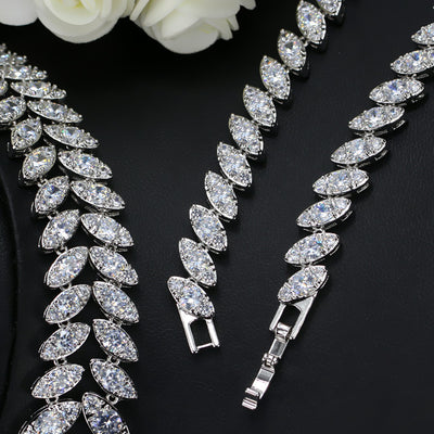 Silver-toned necklace and earring set with red teardrop stones and clear marquise-cut accents on a black display. - Image 4