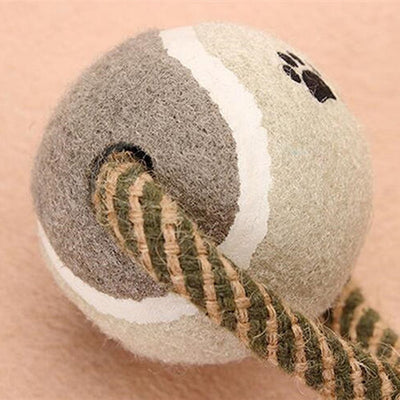 Braided rope dog chew toy with two tennis balls featuring paw prints, shown with a dog holding a similar toy. - Image 8
