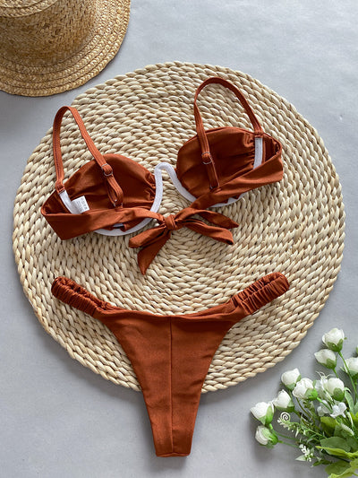 Rust underwire bikini set with ruched top and high-cut bottom, displayed on a woven mat. - Image 14