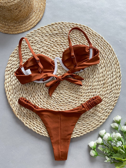 Rust underwire bikini set with ruched top and high-cut bottom, displayed on a woven mat. - Image 14