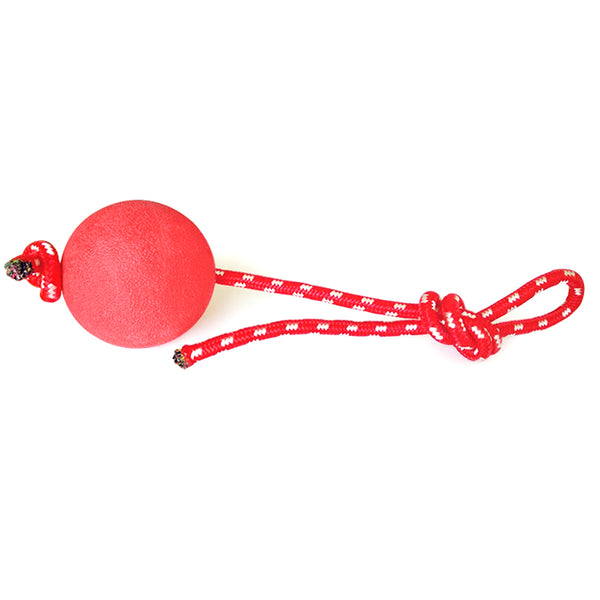 Red solid rubber elastic ball with a red and white braided rope, designed as a durable dog chew and training toy.