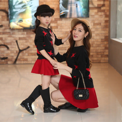 Mother and child wearing matching navy blue plaid overalls with white long-sleeve shirts, holding hands.