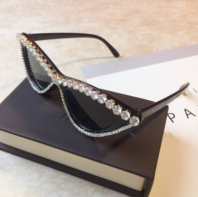 Two pairs of cat-eye sunglasses, one black with clear rhinestones and one pink with pink rhinestones, on a light surface. - Image 3