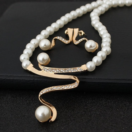 White pearl necklace and matching stud earrings set with gold-tone wavy metal and clear crystal accents.
