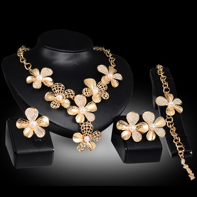 Gold-tone four-piece jewelry set with flower motifs, featuring a necklace, bracelet, ring, and earrings, all with faux pearls and clear rhinestones. - Image 5