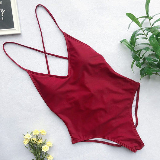 Light blue backless one-piece swimsuit with thin straps, made of polyester, laid flat on a wooden surface. - Image 10