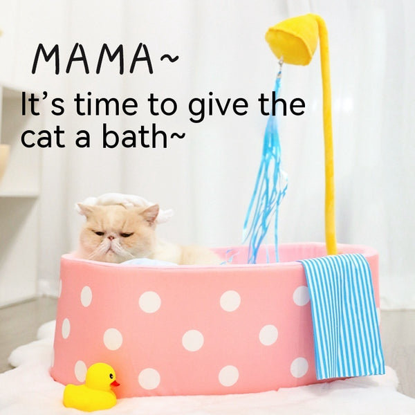 Pink polka dot pet bed shaped like a bathtub with a yellow showerhead toy and blue streamers, plus a blue striped 'towel'.