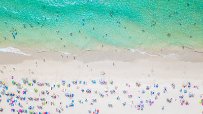 Aerial view of a vibrant summer beach with turquoise water, white sand, and colorful umbrellas.