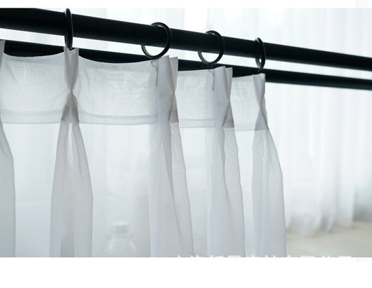 Sheer pink rod pocket curtain hanging on a black curtain rod, offering light transmission for a modern room. - Image 13