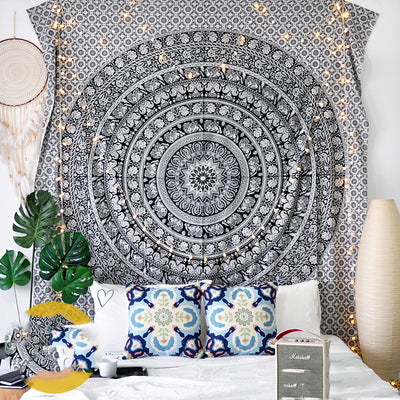 Black and white mandala tapestry with string lights hanging above a bed with blue and white patterned pillows. - Image 6