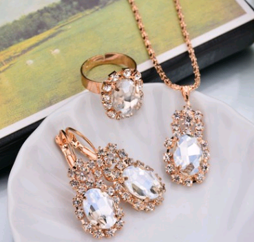 Rose gold-toned necklace, earrings, and ring set with large oval clear gemstones surrounded by smaller stones. - Image 18