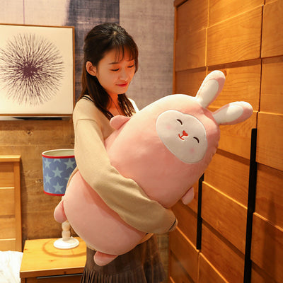 Pink rabbit plush doll with closed eyes, soft and elongated, standing on a bed. - Image 4