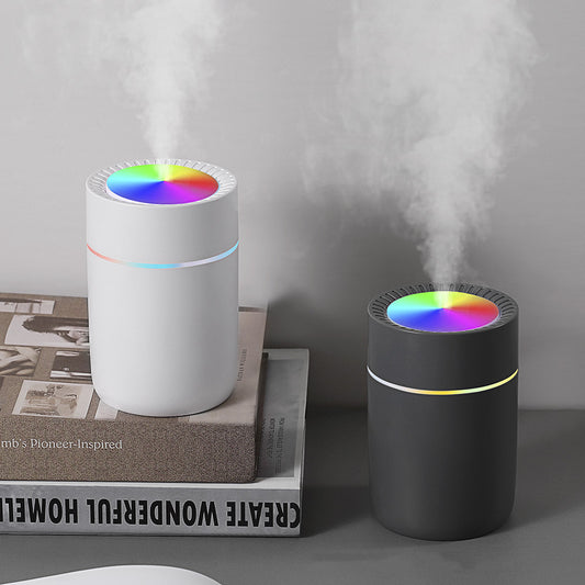 Dark gray cylindrical humidifier with a rainbow LED light ring on top and a thin, colorful LED band around its body.