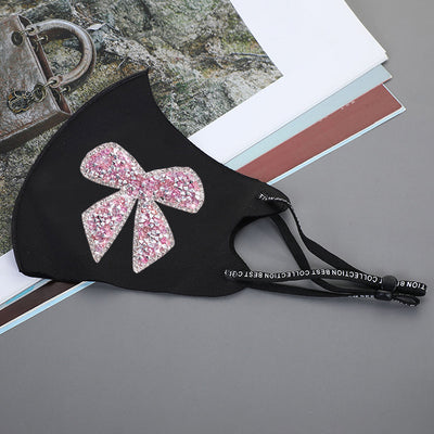 Black ear-mounted mask with a sparkling rhinestone bow pattern, featuring adjustable ear loops. - Image 18