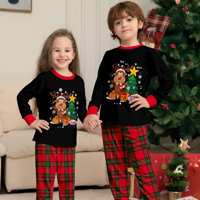 Two children in black and red plaid Christmas pajamas with a reindeer and Christmas tree graphic, standing by a Christmas tree. - Image 7