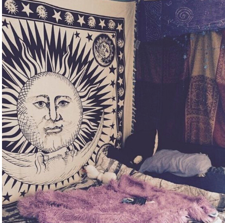 Black and white mandala tapestry with intricate geometric patterns hanging above a bed in a bedroom.
