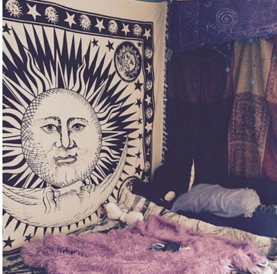 Black and white mandala tapestry with intricate geometric patterns hanging above a bed in a bedroom.