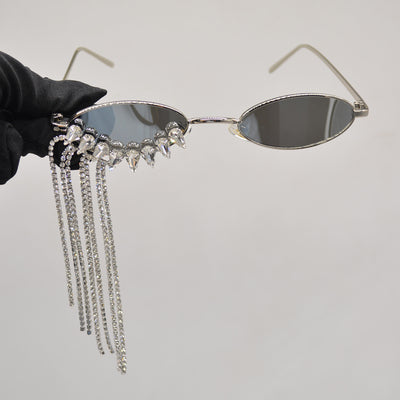 Silver oval-frame sunglasses with mirrored lenses and glamorous rhinestone tassels on one side, held by a gloved hand. - Image 3