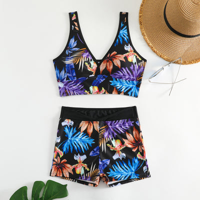 Two-piece swimsuit with a black background and vibrant pink and purple tropical floral print. Features a V-neck crop top and high-waisted boxer shorts. - Image 6