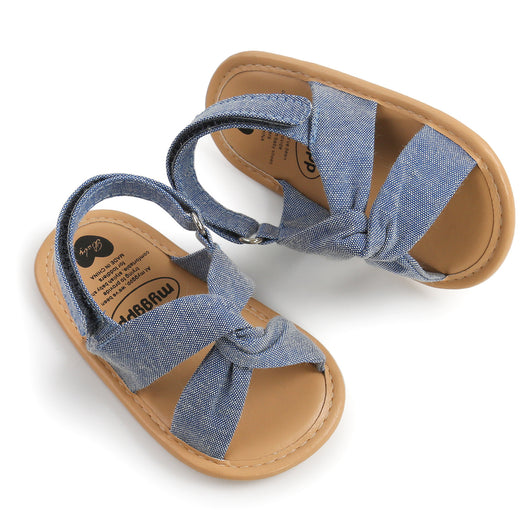 Black baby sandals with knotted cross straps and a matching black floral headband on a white background. - Image 39