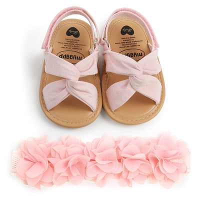Black baby sandals with knotted cross straps and a matching black floral headband on a white background. - Image 13