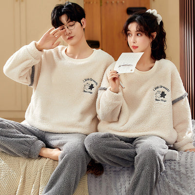 Couple wearing matching cream coral fleece pajamas with gray pants and bear embroidery, seated on a bed. - Image 4