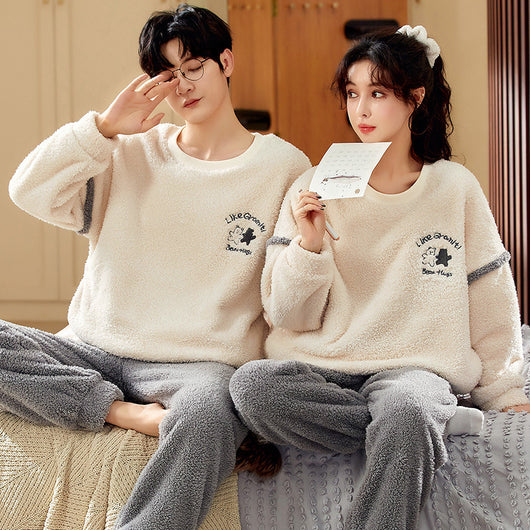 Couple wearing matching cream coral fleece pajamas with gray pants and bear embroidery, seated on a bed. - Image 4
