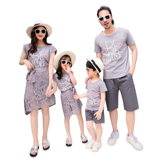 Family of four in matching grey "BE MINE" outfits. Mother and daughter wear lace skirts, father and son wear shorts.
