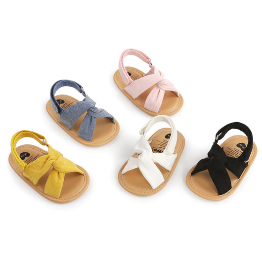 Black baby sandals with knotted cross straps and a matching black floral headband on a white background. - Image 4