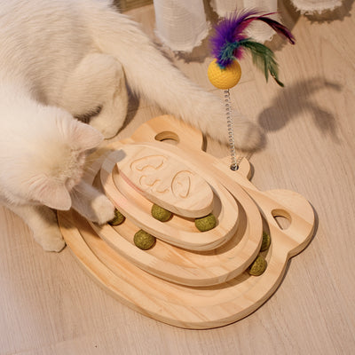 White cat playing with a wooden multi-level track toy featuring a spring-mounted yellow feather ball and a green catnip ball. - Image 16