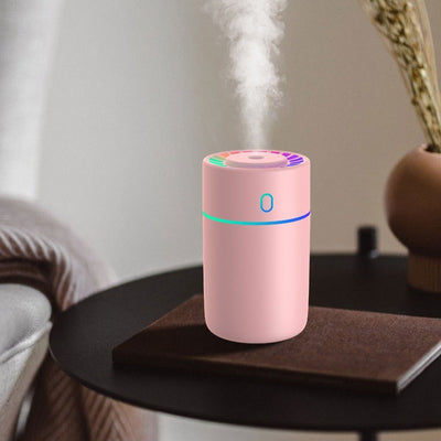 Pink cylindrical humidifier with a colorful LED light ring on top and a blue-green light band around its middle. - Image 7