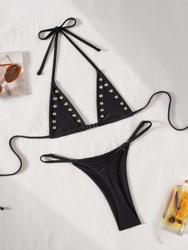 Black tie-front bikini swimsuit with silver grommets on the triangle top and a ruched thong bottom, laid flat. - Image 6