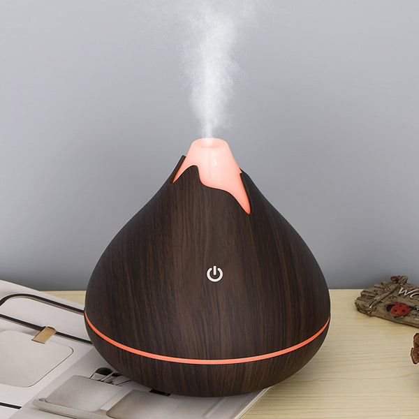 Teardrop-shaped aromatherapy humidifier with light wood grain finish, emitting mist and glowing with purple LED light. - Image 3