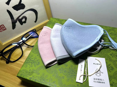 Dark gray cotton head-mounted mask with adjustable ear loops, shown in packaging on a patterned green surface. - Image 23