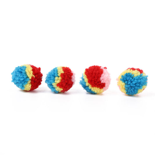 A hand holds a fluffy rainbow pom-pom ball toy, with another colorful ball in the background. - Image 2
